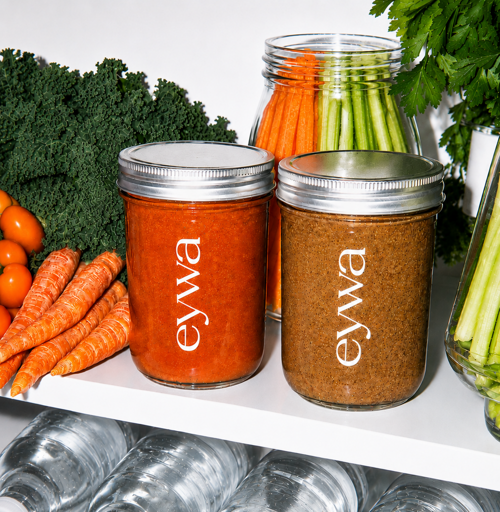 Two jars of food with 'eywa' branding on a shelf with vegetables and water bottles.
