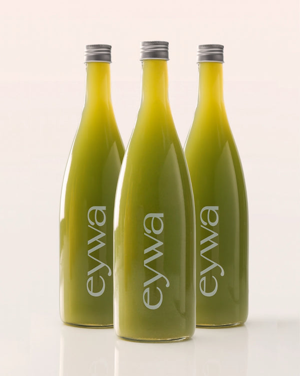 Three green organic celery juice bottles with 'eywa' branding on a white background