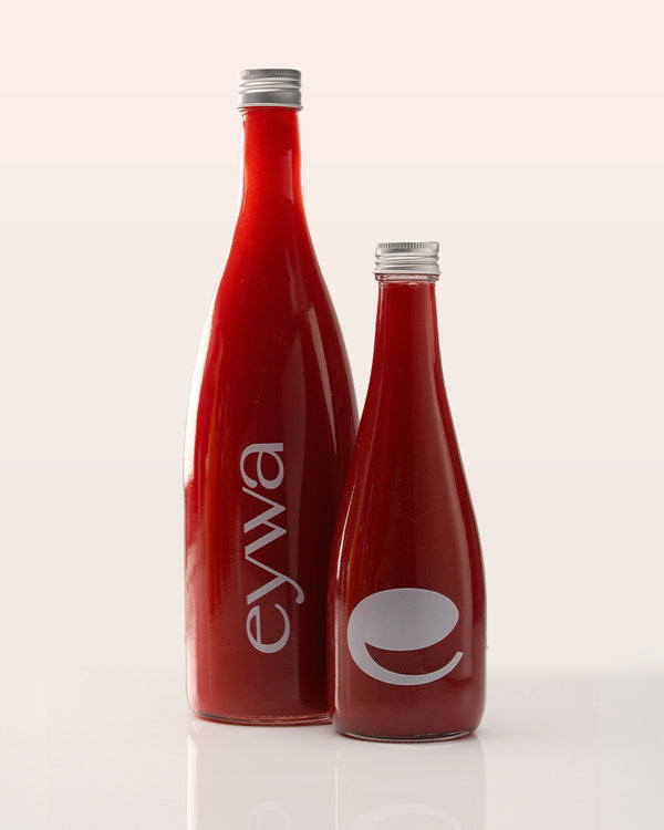 Two red organic watermelon juice bottles with 'eywa' branding on a white background